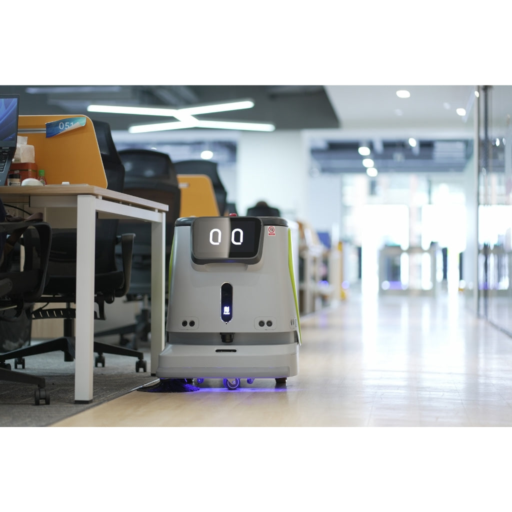 PUDU CC1 operating in a busy open-plan office environment near desks and workstations.