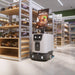 PUDU ET1 compact scrubber dryer robot cleaning a convenience store aisle with its advertising display