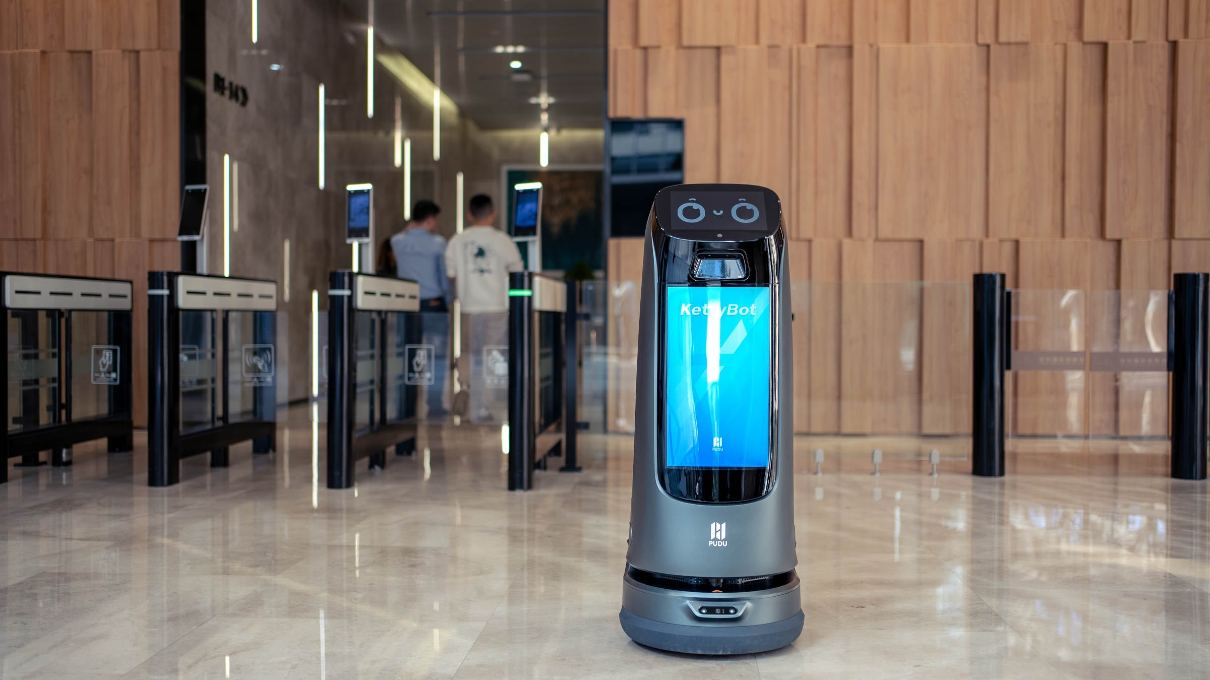 PUDU KettyBot Pro delivery and reception robot in office lobby next to seating area