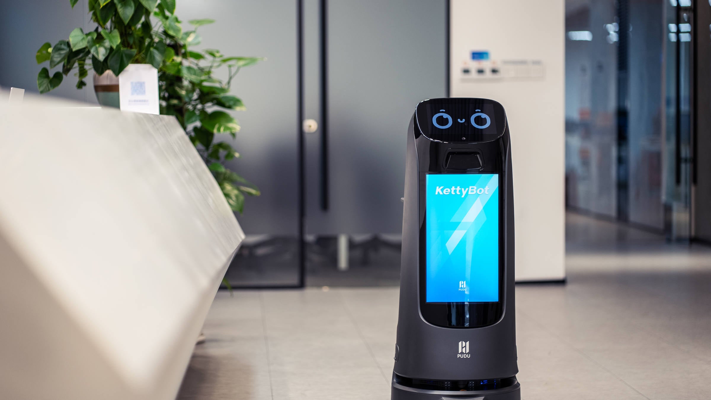 PUDU KettyBot Pro delivery and reception robot in corporate building entryway with access gates