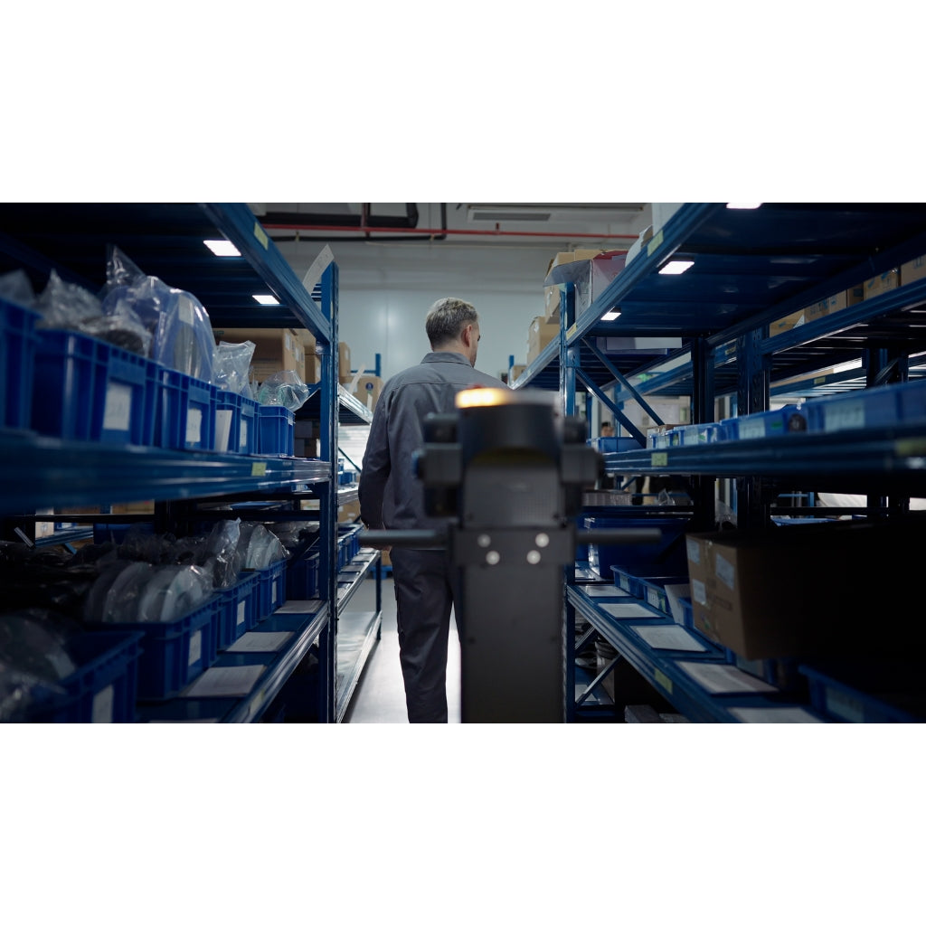 PUDU T300 navigating a narrow warehouse aisle between blue shelving units, demonstrating compact design.