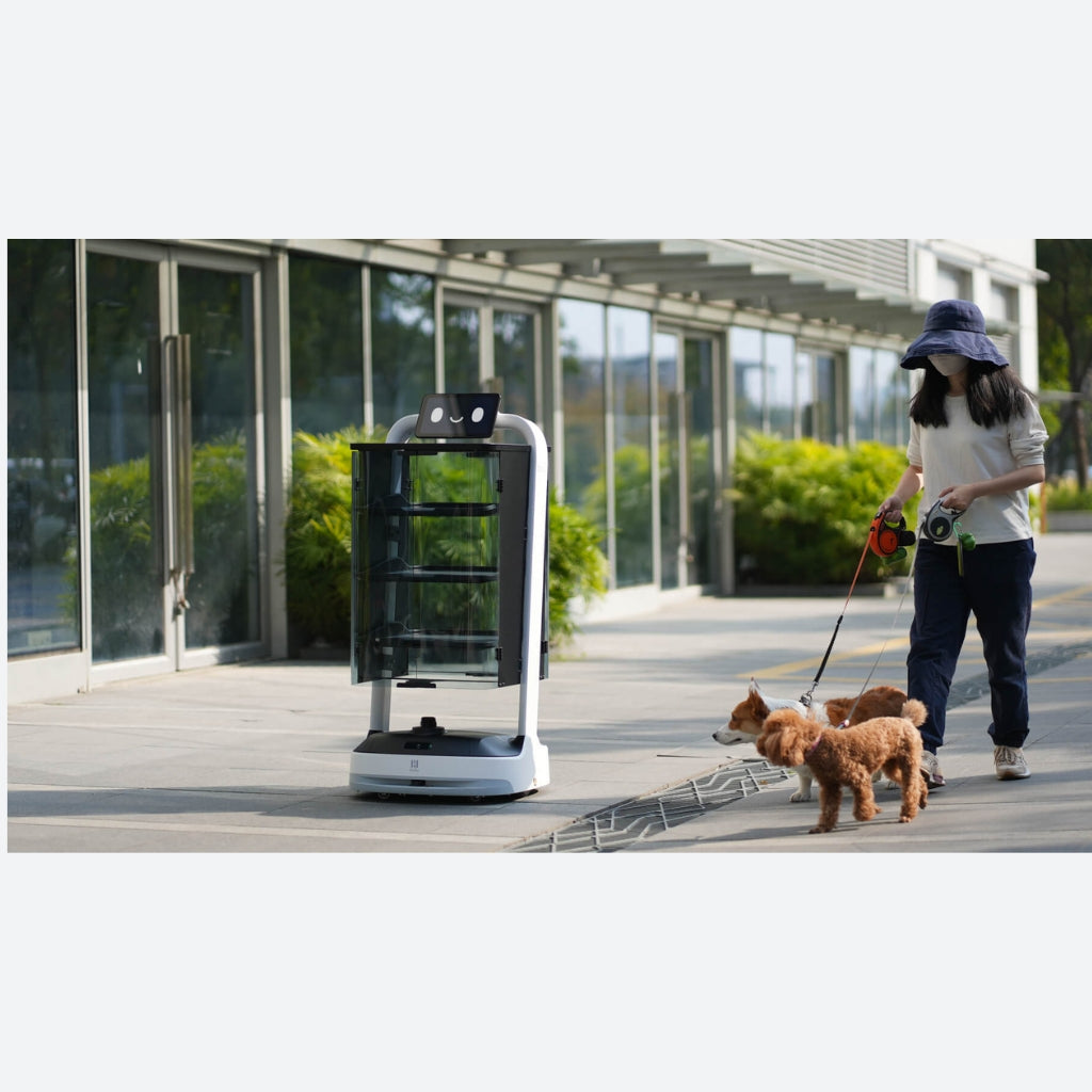 PuduBot 2 delivering outdoors on a paved pathway, demonstrating IP42 weather resistance and semi-outdoor capability.
